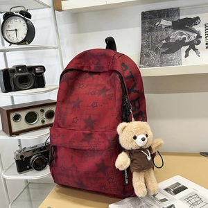 Dettaglio dello zaino rosso con stelle nere e portachiavi a forma di orsetto di peluche