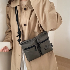 Detail view of nylon crossbody bag featuring double front zip pockets and rope strap