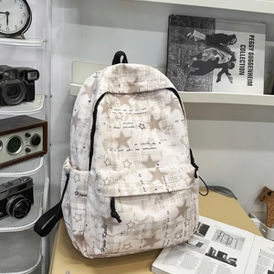Dettaglio ravvicinato di uno zaino in tela beige con motivo a stelle e tasche laterali