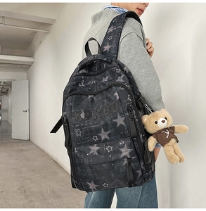 Close-up of black backpack featuring star patterns and a cute brown bear charm