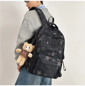 Detail of black backpack with star pattern, KRXBD logo, and cute brown bear keychain charm