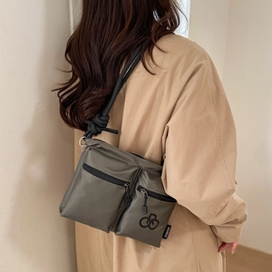 Detail of waterproof olive green nylon crossbody bag with rope shoulder strap and pockets