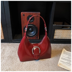 Detailed macro of the red glossy leather underarm bag featuring a large silver buckle