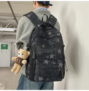 Detail view of dark grey backpack featuring star patterns and a cute plush bear charm
