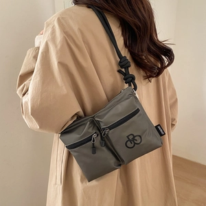 Detail view of water-resistant nylon crossbody bag with double zippers and rope strap