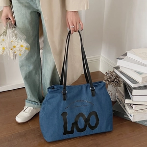 Detail of blue denim tote bag featuring black LOO art font and shoulder straps