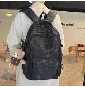 Detail of grey canvas backpack with star pattern and cute teddy bear charm accessory