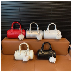 Detail view of colorful Boston bags in leather with plush sheep charms on a bench