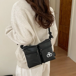 Detail of black nylon crossbody bag with dual zip pockets and knotted shoulder strap
