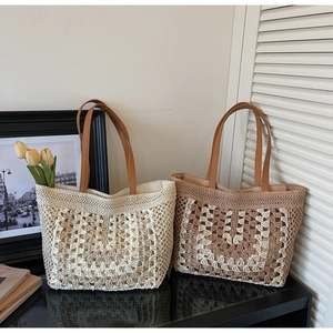Close-up of hand-woven straw tote bags with brown leather handles in two-tone patterns
