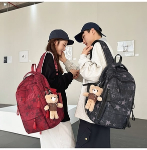 Close-up of minimalist school backpacks with star patterns and cute bear plush charms