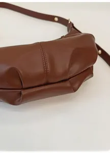 Detailed close-up of pleated bottom design and texture on brown leather shoulder bag