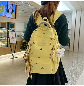 Dettaglio dello zaino in nylon giallo con ricami a farfalla e ciondolo a sfera di peluche
