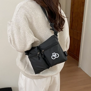 Detail view of black nylon crossbody bag featuring multi-pocket design and knotted strap