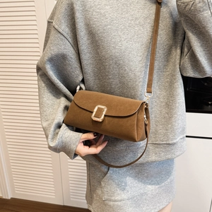 Dettaglio di una borsa a tracolla in pelle scamosciata marrone con fibbia dorata su modella