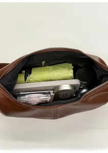 Spacious interior of brown leather pleated bag showing zippered pocket and essentials
