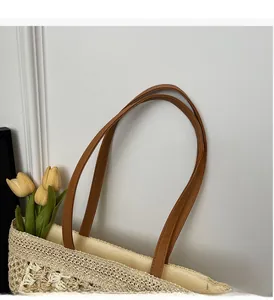 Close-up of woven straw tote bag with durable brown synthetic leather shoulder handles