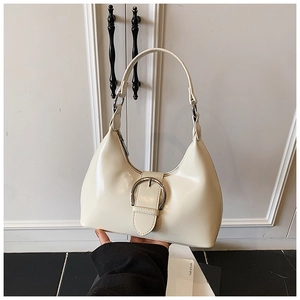 Detailed macro view of cream-white leather handbag with a large silver decorative buckle