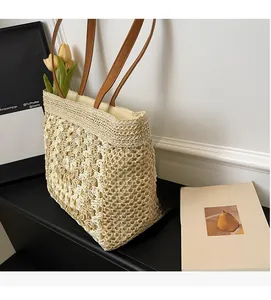 Detail view of woven straw tote bag featuring intricate crochet patterns and leather straps