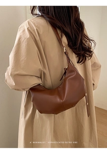 Close-up of brown pleated hobo bag with smooth PU leather finish and adjustable strap