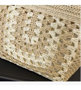 Macro detail of the hand-woven hollow crochet texture on a cream straw beach tote bag