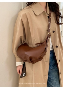 Detail of dark brown pleated crossbody bag with metal eyelets on adjustable strap