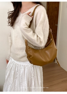 Caramel crescent moon bag featuring vertical stitching and adjustable gold metal buckle detail