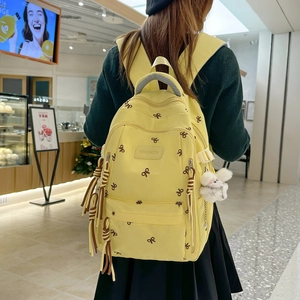 Zaino giallo con stampa a farfalla e ciondolo in peluche indossato da una modella