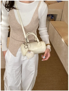 Detail view of cream white Boston bag with plush charm and metal ring on stylish PU leather