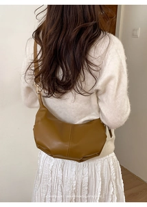 Detail of tan leather crossbody croissant bag with adjustable strap and golden hardware buckle