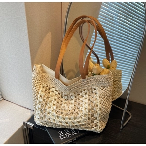 Detail of crochet straw tote bag with intricate patterns and brown leather handle