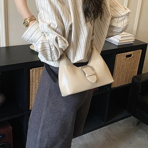 Detail of off-white hobo bag with a prominent silver metal buckle and minimalist leather finish