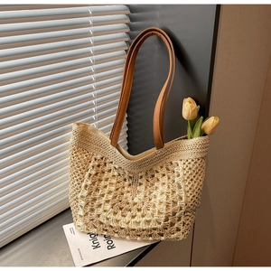 Detail of hand-woven straw tote bag showing intricate crochet patterns and brown leather straps