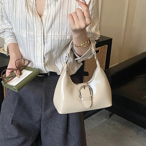 Detail of beige hobo bag with large silver metal buckle and glossy finish texture