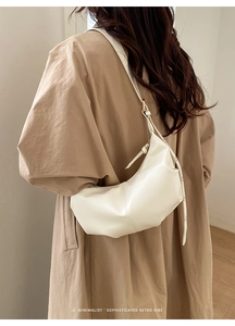 Minimalist white pleated dumpling bag worn with a khaki trench coat for a retro vibe