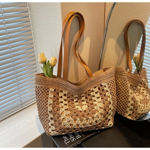Close-up of hand-woven straw tote bag with brown leather straps and geometric pattern