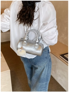Detail of silver metallic cylinder bag with handle and plush charm accessory