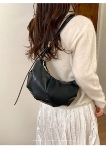 Detailed side view of minimalist black pleated dumpling bag with adjustable shoulder strap