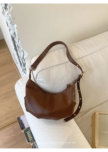 Close-up of caramel leather hobo bag with gold rivets and smooth minimalist finish