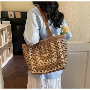 Macro shot of large straw tote bag featuring detailed beige crochet and leather straps