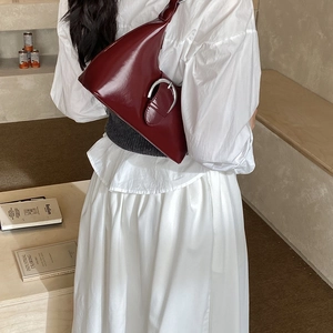 Detail view of burgundy leather underarm bag with large silver metal buckle on strap