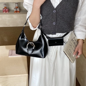 Detail of black glossy leather baguette bag with silver buckle in French style setting