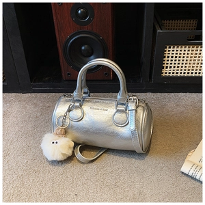 Close-up of silver cylinder boston bag with metallic texture and plush sheep charm