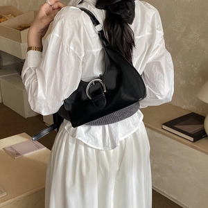 Detail of a vintage black leather underarm bag with a large silver buckle on a model