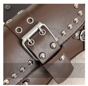 Macro shot of brown leather vintage handbag featuring silver studs and metal buckle detail