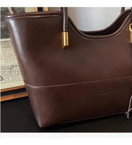 Detailed macro view of high-quality dark brown leather texture and metal accents on tote bag