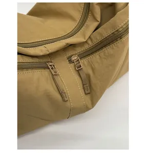Detailed close-up of khaki nylon ripstop fabric and smooth double zipper track on the bag