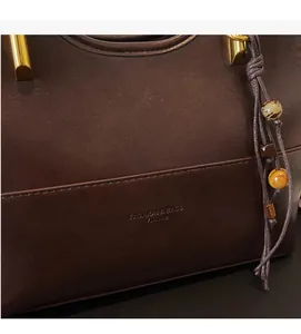 Detail of a brown PU leather tote bag with vintage texture and gold metallic handle accents