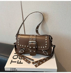 Detail of a brown leather shoulder bag featuring silver rivets and punk style metallic buckles