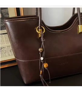 Detail view of brown vintage tote bag with wooden bead tassels and gold ring accents